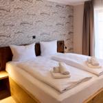 Zimmer mit Doppelbett, Fischmotivwand und Fenster mit Vorhängen.