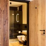 Badezimmer mit Dusche, Toilette und Waschbecken. Holztüren und Wand mit Wal-Motiv.