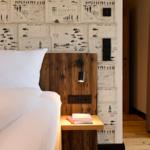 Schlafzimmer mit Bett, Nachttisch und dekorativer Wandverkleidung.