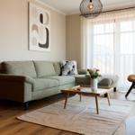 Ein Wohnzimmer mit Sofa, Couchtisch und Sessel. Durchgang zur Schlafzimmerseite.