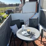 Terrasse mit runden Tisch, zwei Stühlen und Kaffeetasse. Blick auf grüne Landschaft.