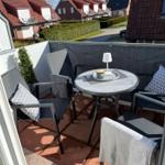 Terrasse mit Tisch, Stühlen und Bezug. Blick auf Wohnhäuser und Straße.