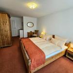 Bedroom with wooden bed, wardrobe, and nightstand. Carpeted floor and ceiling light.