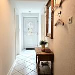 Hallway with wooden bench, mirror, and hooks on wall. Door at the back.