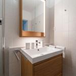 Badezimmer mit Waschbecken, Spiegel und Dusche.