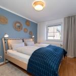 Schlafzimmer mit Bett, Fenster und Wanddekoration.