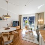 Wohn- und Essbereich mit Holzboden, Sofa, Esstisch und Balkonansicht.