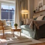 Ein Wohnzimmer mit Sofa, Sessel, Tisch und Fenster zur Terrasse.