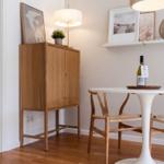 Esszimmer mit Tisch, Stühlen und Holzschränkchen. Wandregal mit Bildern und Dekoration.