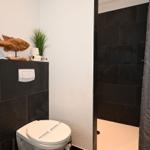 Badezimmer mit Toilette, Dusche und Holzdekoration.