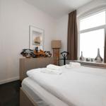 Schlafzimmer mit Bett, Fenster und dekorativen Gegenständen.