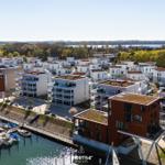 Modern residential area by the harbor with boats and green spaces.