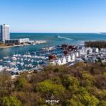 Harbor town with yachts, boat houses, and view of the sea.
