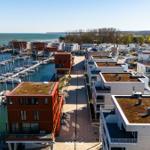 Harbor town with boats and modern buildings with green roofs.