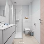 Badezimmer mit Dusche, Waschbecken und Toilette. Moderne Einrichtung mit hellen Fliesen.