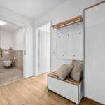 Eingangsbereich mit Schuhschrank, Spiegel und Toilettenbereich im Hintergrund.