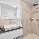 Bad mit Dusche, Waschbecken und Spiegel