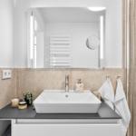 Badezimmer mit Waschbecken, Spiegel und Dusche.