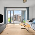 Wohnzimmer mit Sofa, TV und Blick auf Balkon