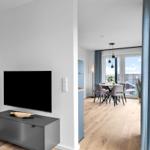 Wohn- und Essbereich mit TV, Holzboden und Blick auf die Dächer.