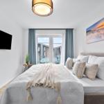 Schlafzimmer mit Bett, TV und Balkonansicht.
