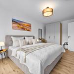 Schlafzimmer mit Bett, Nachttisch, Wandbild und Schrank.