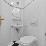 Badezimmer mit Toilette, Waschbecken und Spiegel an weißen Wänden.