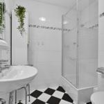 Badezimmer mit Dusche, Waschbecken und Toilette. Schwarze und weiße Fliesen.