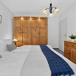 Schlafzimmer mit Holzschrank, Bett und Schminktisch mit Spiegel.