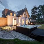 Moderne Villa mit Whirlpool, Garten und Holzverkleidung. Außenbereich mit Sitzgelegenheiten.