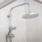 Shower head with handheld shower and chrome fixture on white tiles.