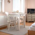 A bedroom with a white desk, chairs, TV, and bed.