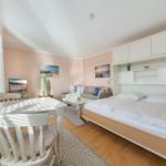 Bedroom with double bed, sofa, dining table, and wall pictures.
