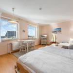 Two beds, sofa, table, and windows with view. Wall art and wardrobe.