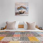 Das Bett mit buntem Quilt und Wandbild eines Boots.
