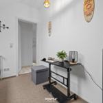 Schlafzimmer mit Bett, Schreibtisch und Kleiderschrank. Wanddekoration und Pflanze sichtbar.