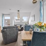 Wohn- und Essbereich mit TV, Sofa, Tisch und Stühlen. Fenster mit Blick nach außen.