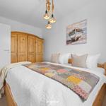 Schlafzimmer mit Holzbett, Kleider schrank und Wandbild mit Boot.