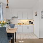 Küche mit Esstisch, weißen Schränken und Fenster. Wanddekoration und Küchenzeile sichtbar.