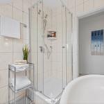 Bad mit Dusche, Badewanne und Handtuchständer.