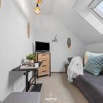 Dachgeschosszimmer mit Sofa, Fernseher und Dachfenster.
