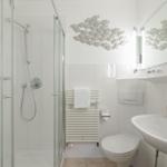 Bathroom with shower, toilet, and sink. Wall decoration of fish.