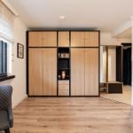 Bedroom with wooden closet, window, and chair. View of outdoor area.