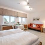 Zimmer mit Doppelbett, Sofa und Fensterblick auf Dächer.