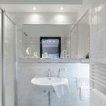 Badezimmer mit Dusche, Waschbecken und Handtuchhalter. Spiegel und Segelboot-Dekoration.