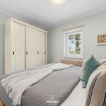 Schlafzimmer mit Bett, Kleiderschrank und Fenster. Wandfarbe hellgrau.