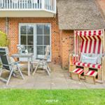 Terrasse mit Strandkorb, Tisch und Stühlen neben Backsteinhaus