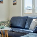 Ein Sofa mit Kissen und Tisch im Wohnzimmer mit Fenster und Wandbildern.