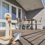 Haus mit Terrasse, Tisch, Stühlen und großer Ankermarke mit Seil.