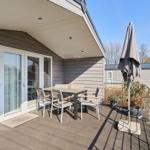 Terrasse mit Tisch, Stühlen und Sonnenschirm. Glas-Türen führen ins Innere.